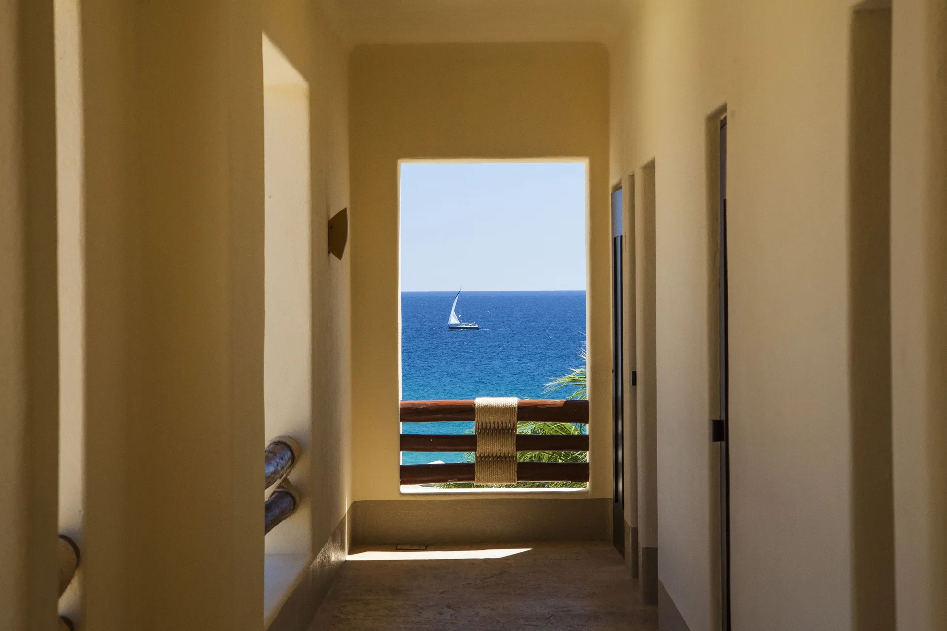 Covered corridor framing a sailboat on the ocean at Pueblo Bonito Pacifica Golf & Spa Resort.