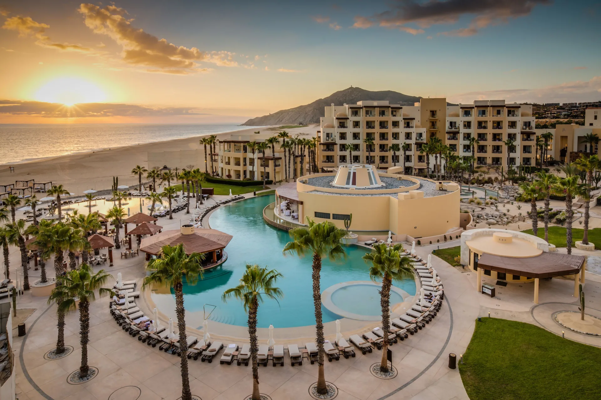 Aerial sunset view of pools, palms, guest buildings, beach, and ocean at Pueblo Bonito Pacifica Golf & Spa Resort.