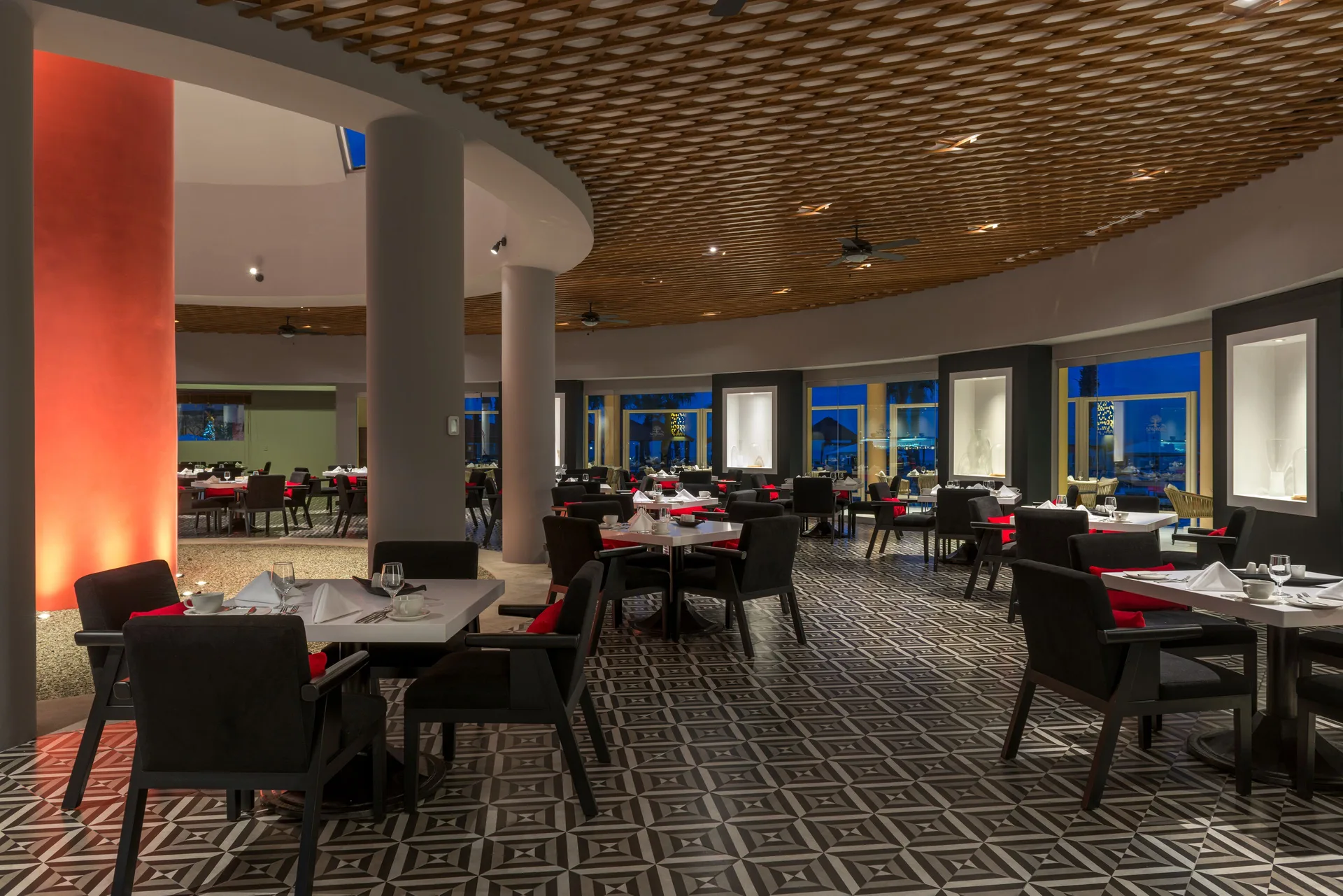 Dining room set with white linens and red accents at Pueblo Bonito Pacifica Golf & Spa Resort.