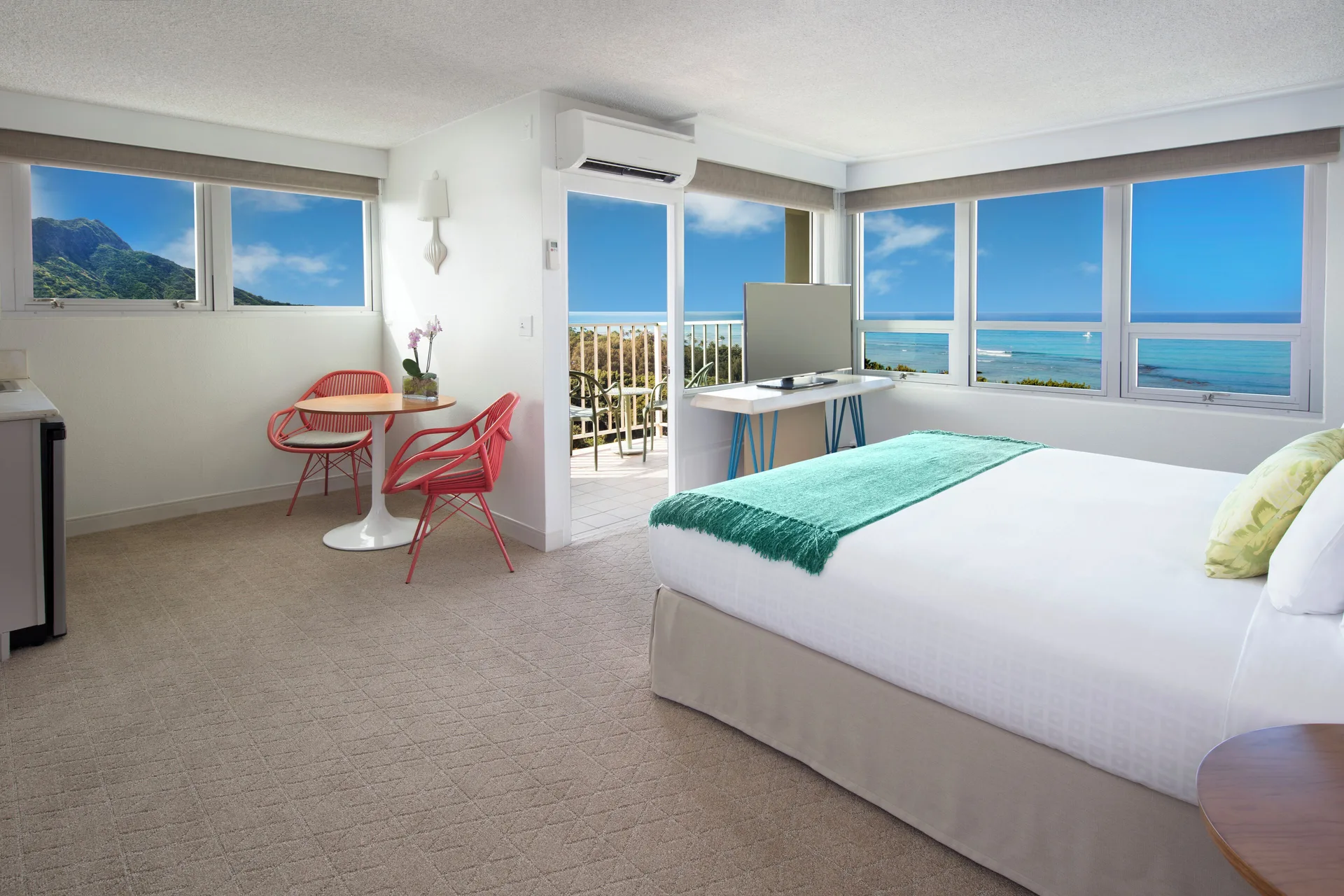 Corner king guest room with balcony and ocean views at Queen Kapiolani Hotel.