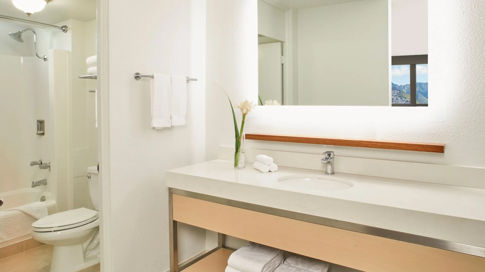 Guest bathroom vanity and tub-shower at Queen Kapiolani Hotel.