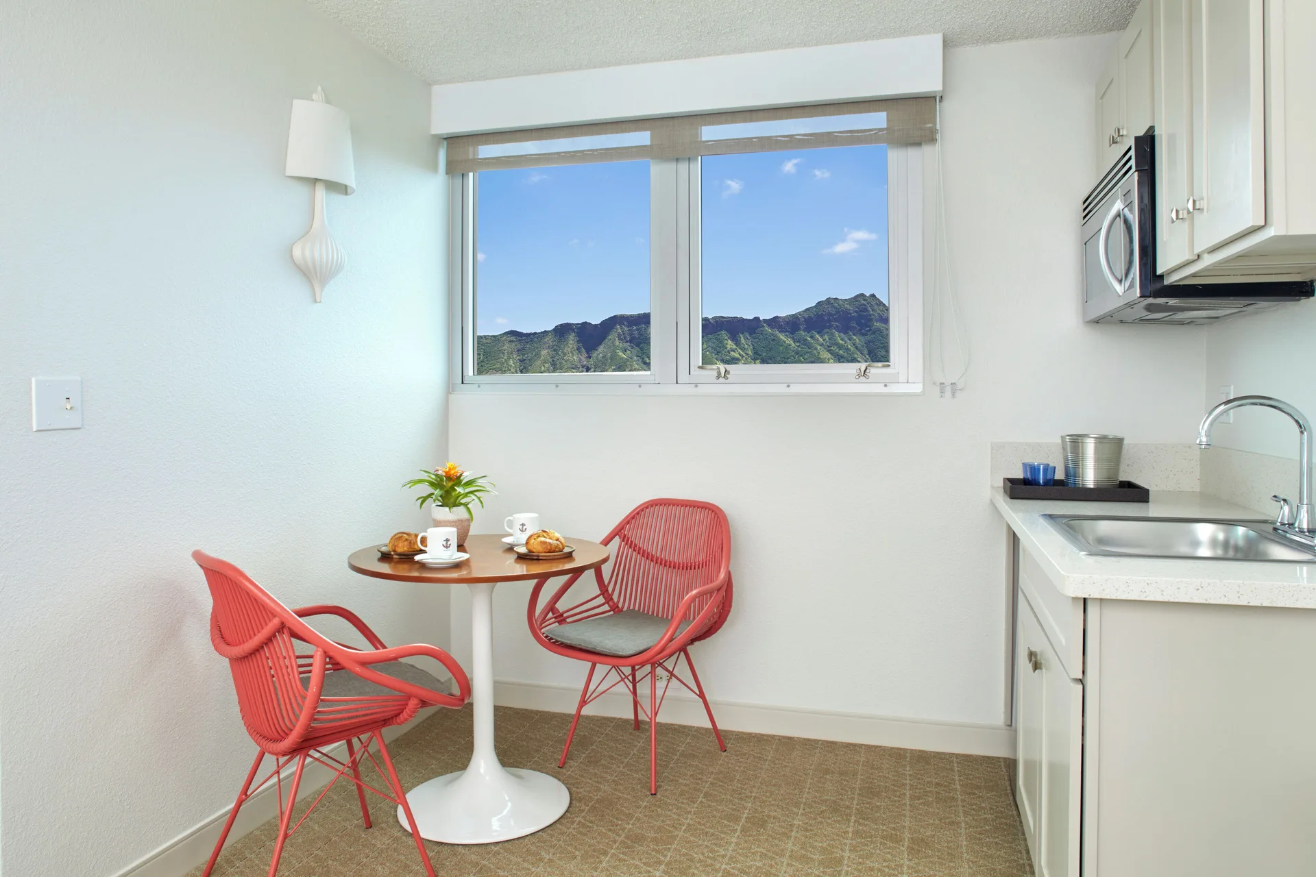A kitchenette and café table face mountain views at Queen Kapiolani Hotel.