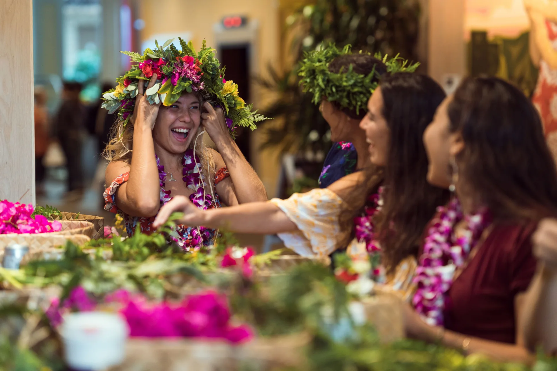Guests make floral lei in a lively indoor activity at Queen Kapiolani Hotel.