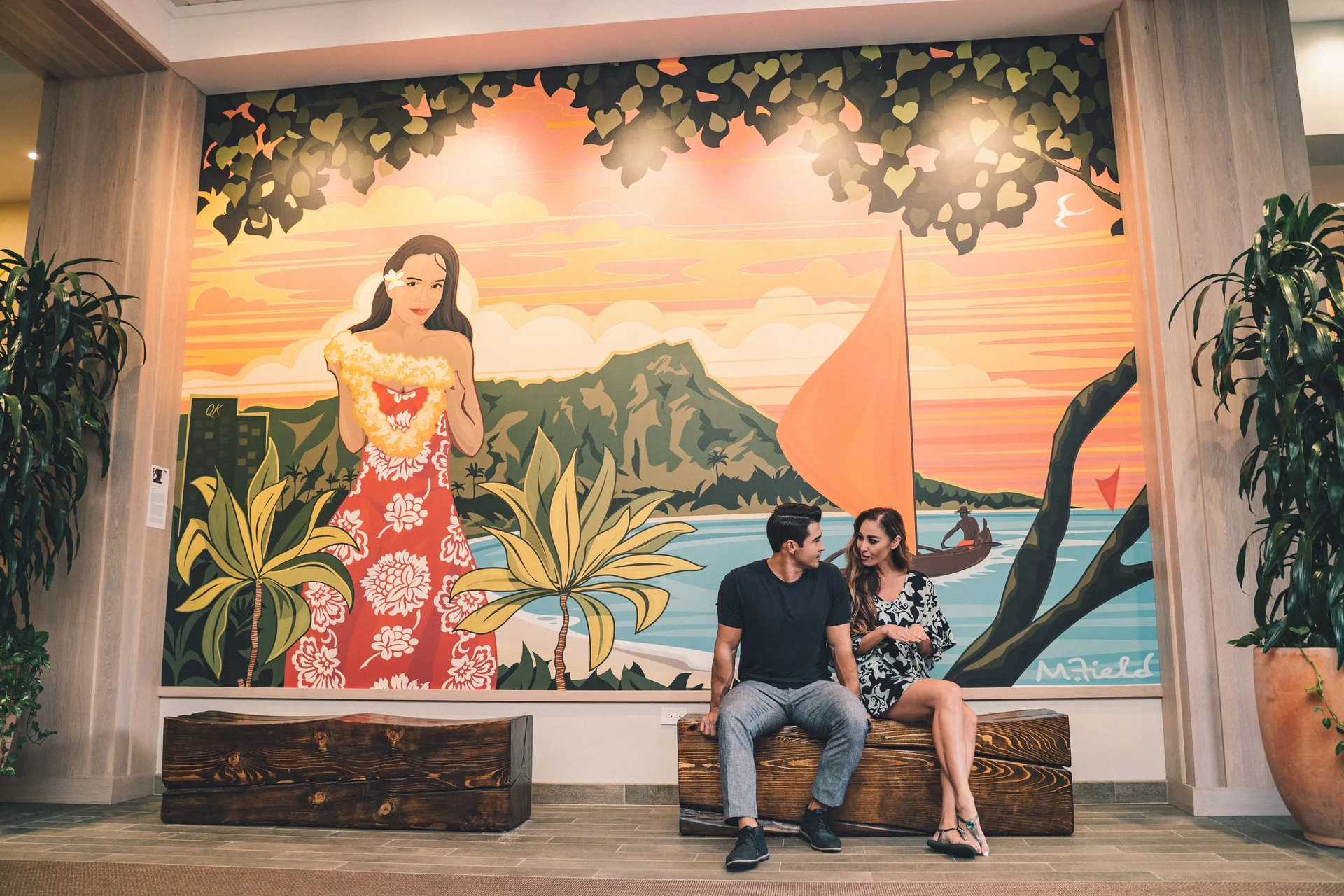 Lobby mural seating area with two guests at Queen Kapiolani Hotel.