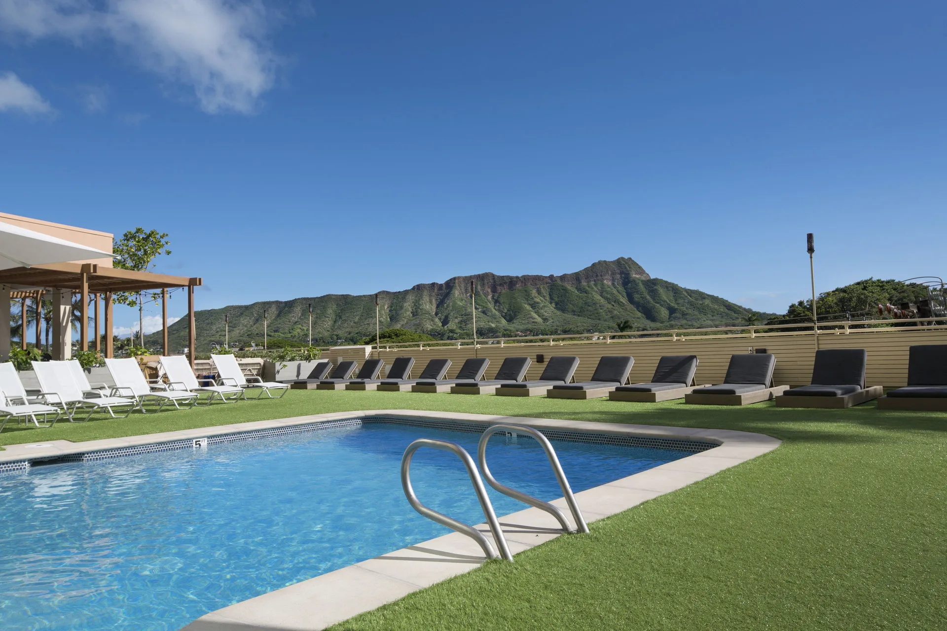 Pool deck with lounge chairs and Diamond Head view at Queen Kapiolani Hotel.