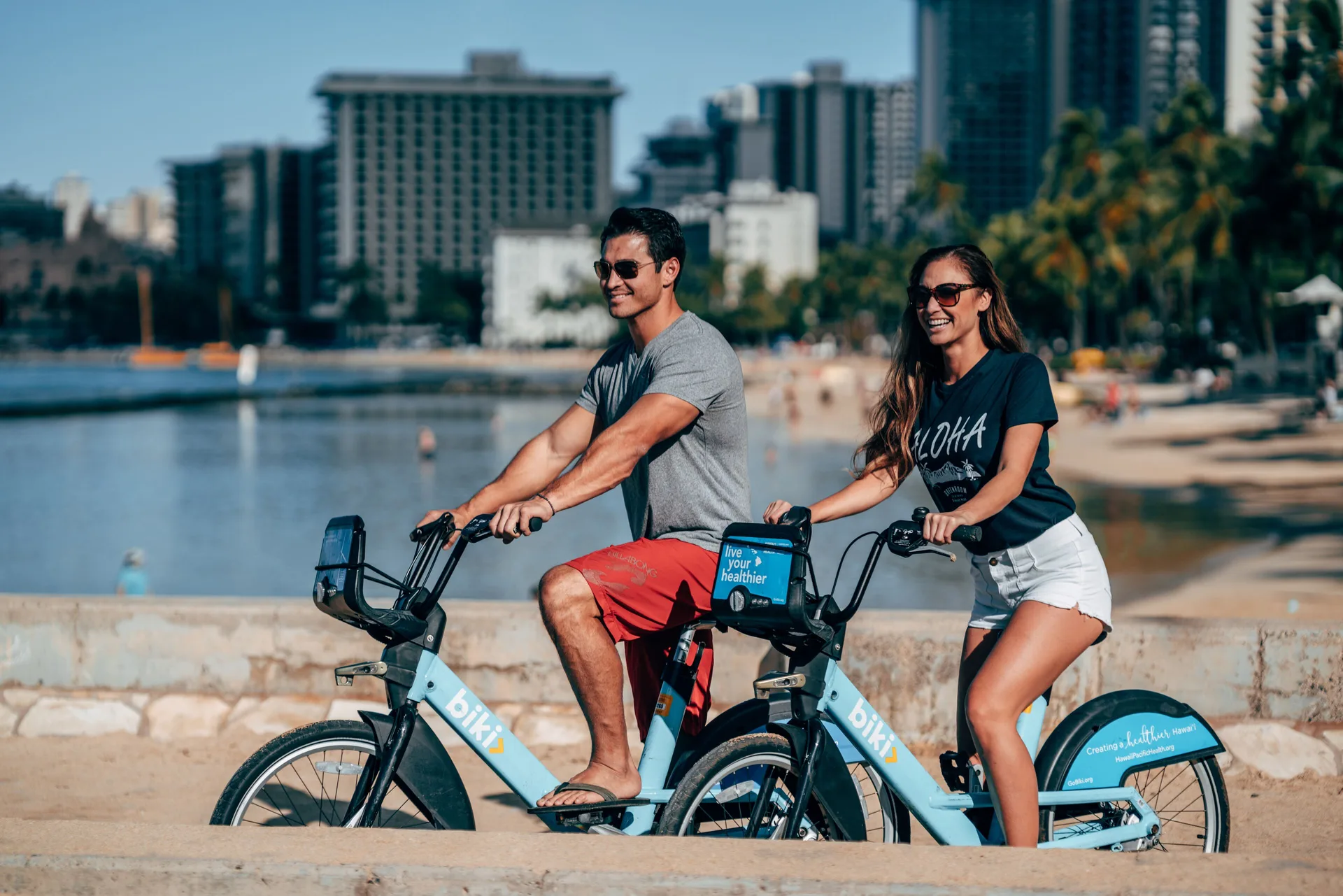 Guests ride bikeshare bicycles along Waikiki near Queen Kapiolani Hotel.