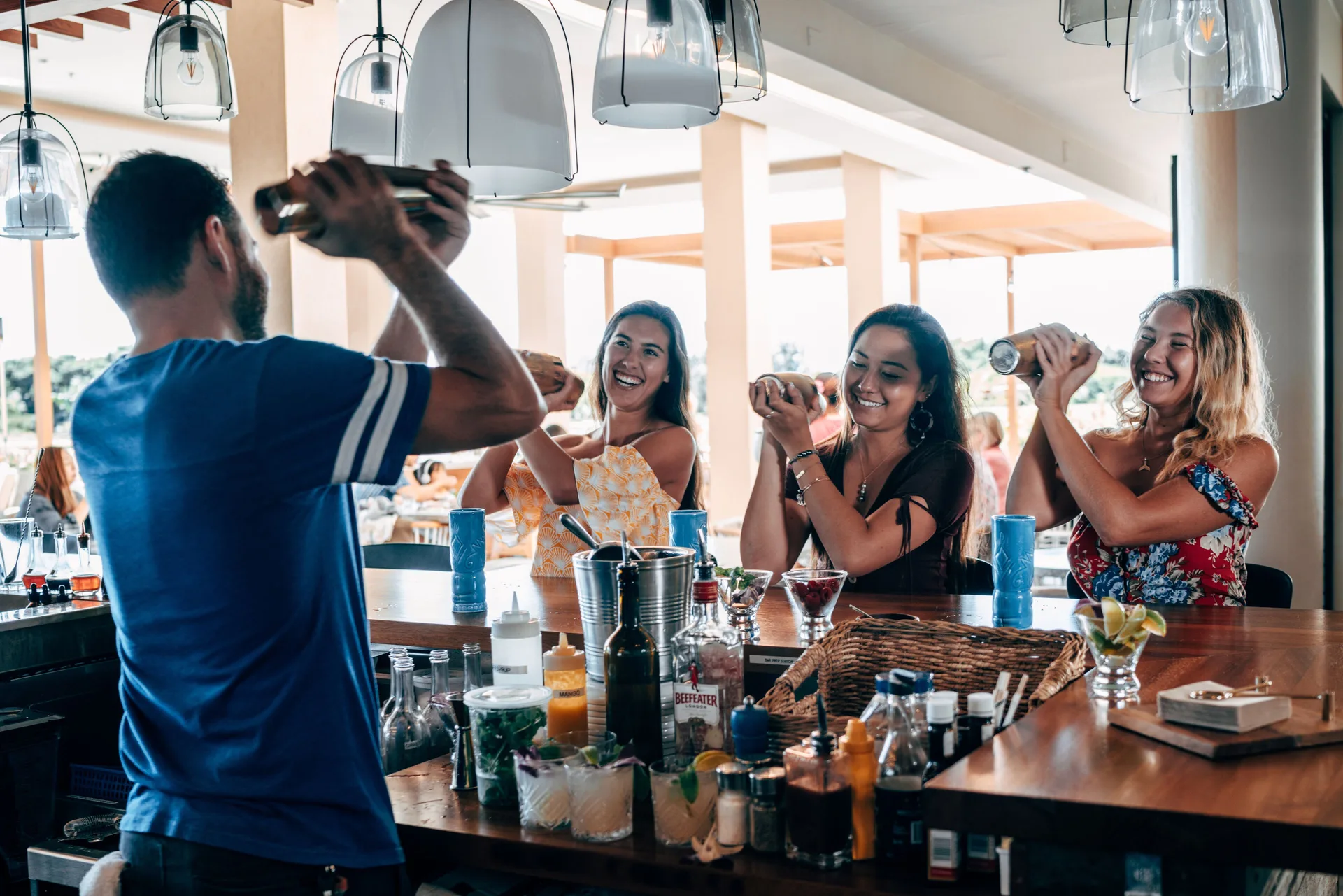 Bartender leading guests in a cocktail-making activity at Queen Kapiolani Hotel.