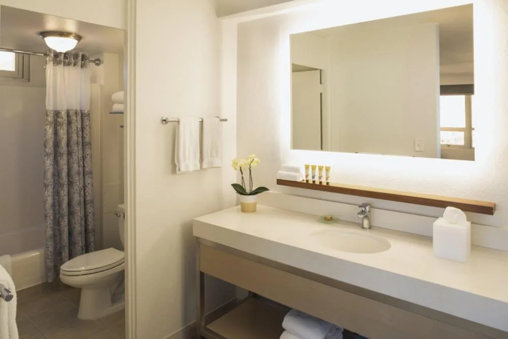 Junior Suite Ocean View bathroom vanity and shower at Queen Kapiolani Hotel.