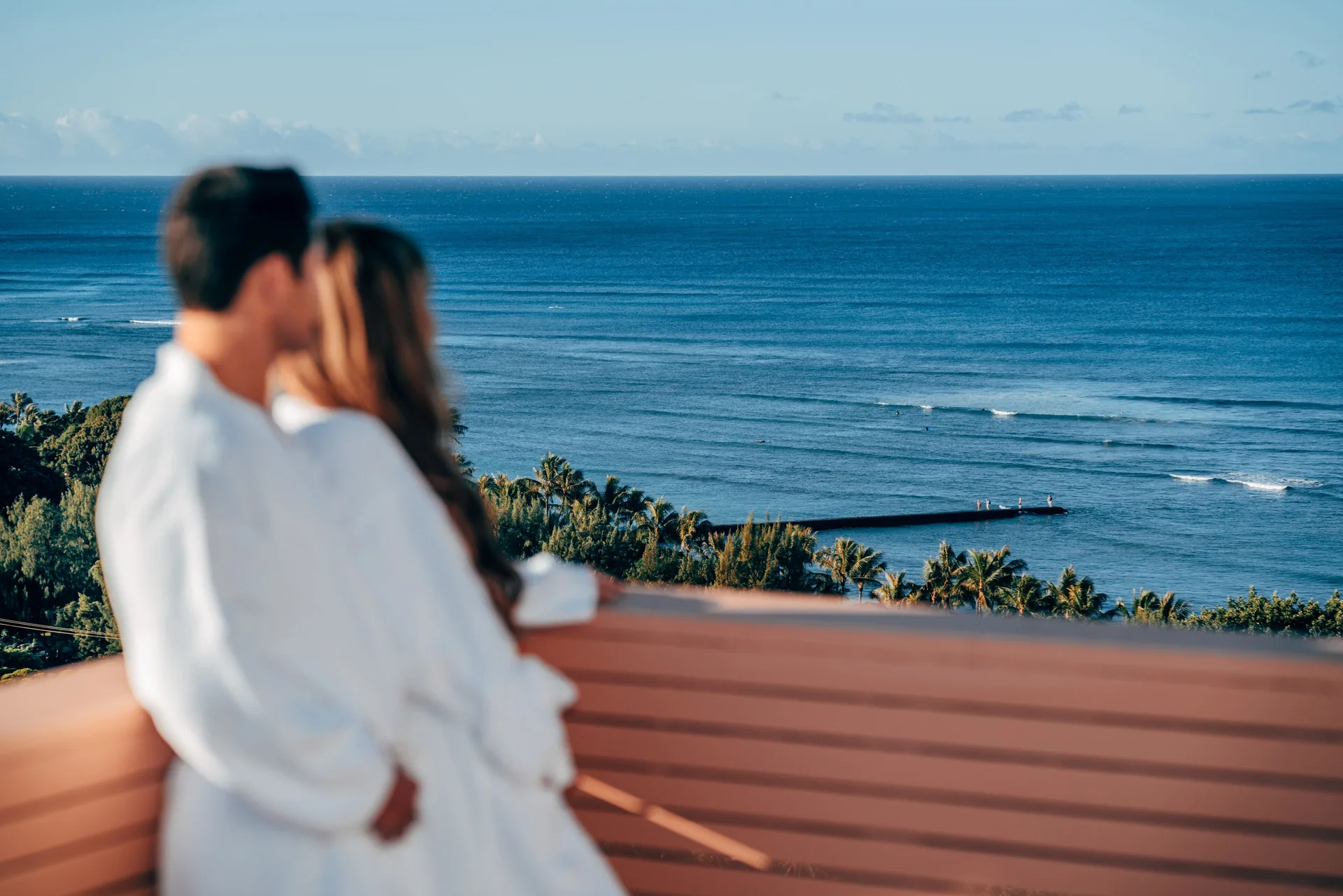 Couple on a balcony overlooking the ocean at Queen Kapiolani Hotel.
