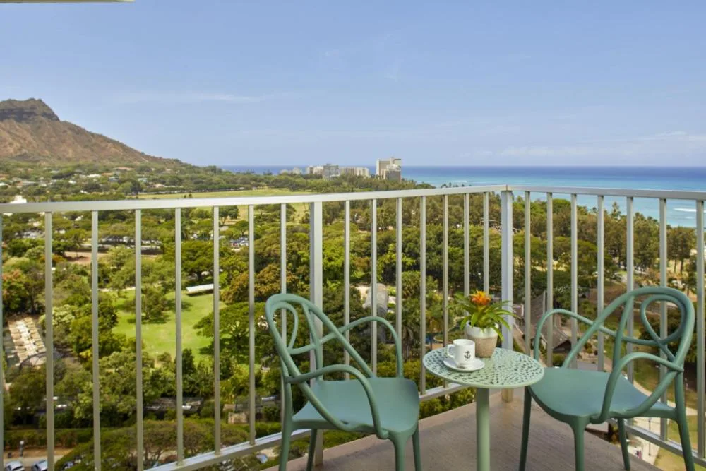 Penthouse One Bedroom Ocean View Suite balcony with chairs and ocean view at Queen Kapiolani Hotel.