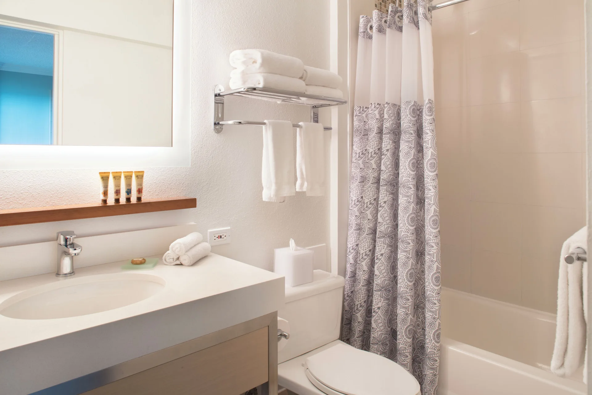 Guest room bathroom with vanity, towels, and tub-shower at Queen Kapiolani Hotel.