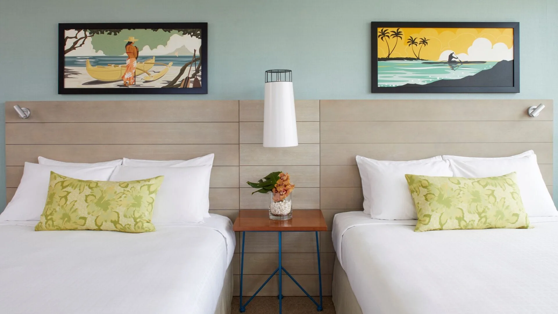 Two white beds with tropical artwork above them at Queen Kapiolani Hotel.