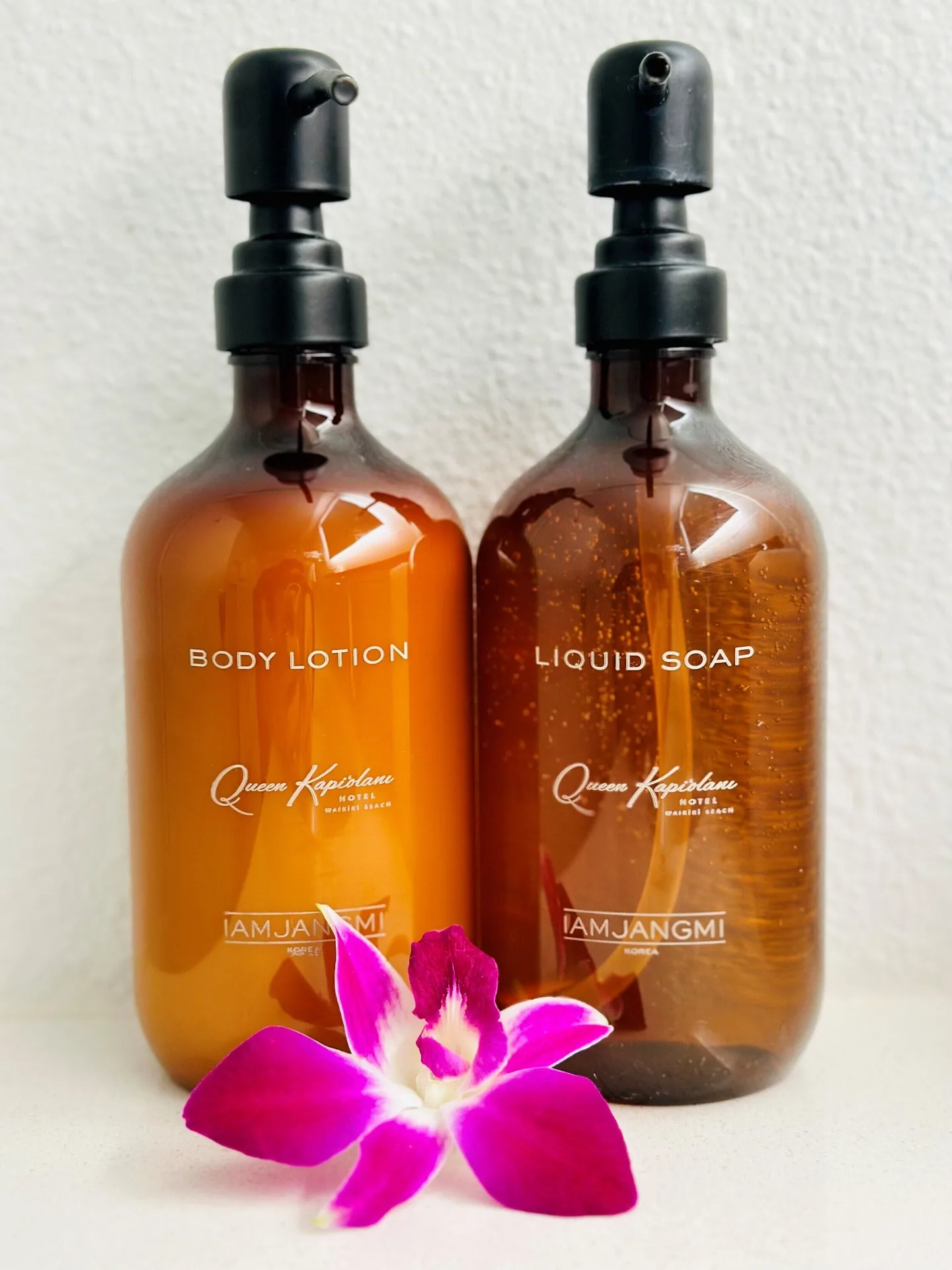 Bathroom lotion and liquid soap bottles with an orchid at Queen Kapiolani Hotel.