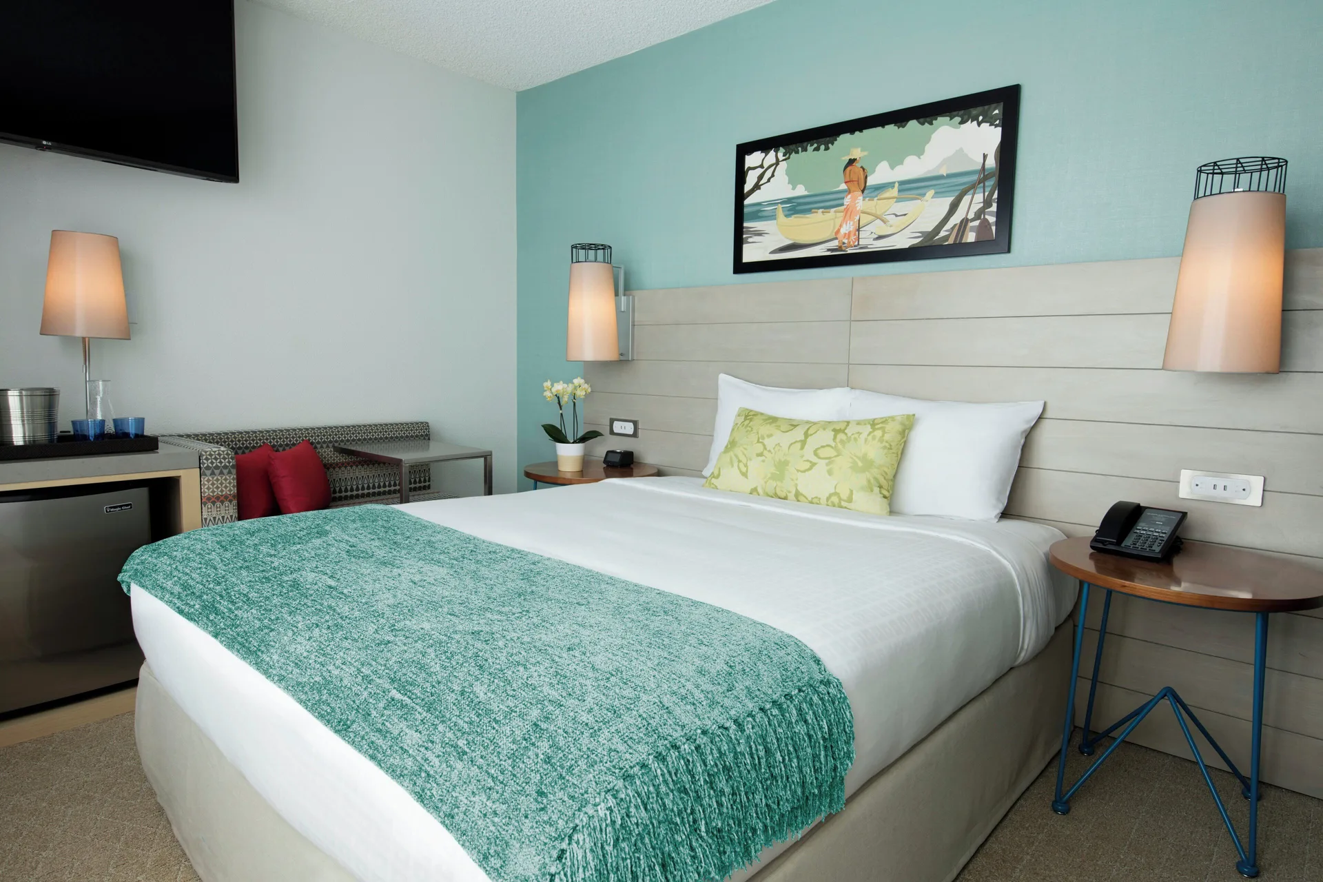 Studio City View king bed, bench, TV, and minibar area at Queen Kapiolani Hotel.