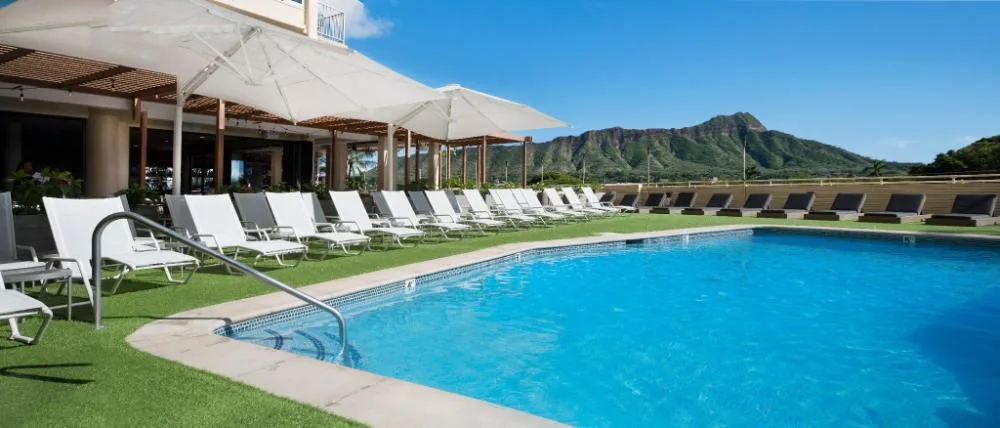 Pool deck with lounge chairs and Diamond Head view at Queen Kapiolani Hotel.