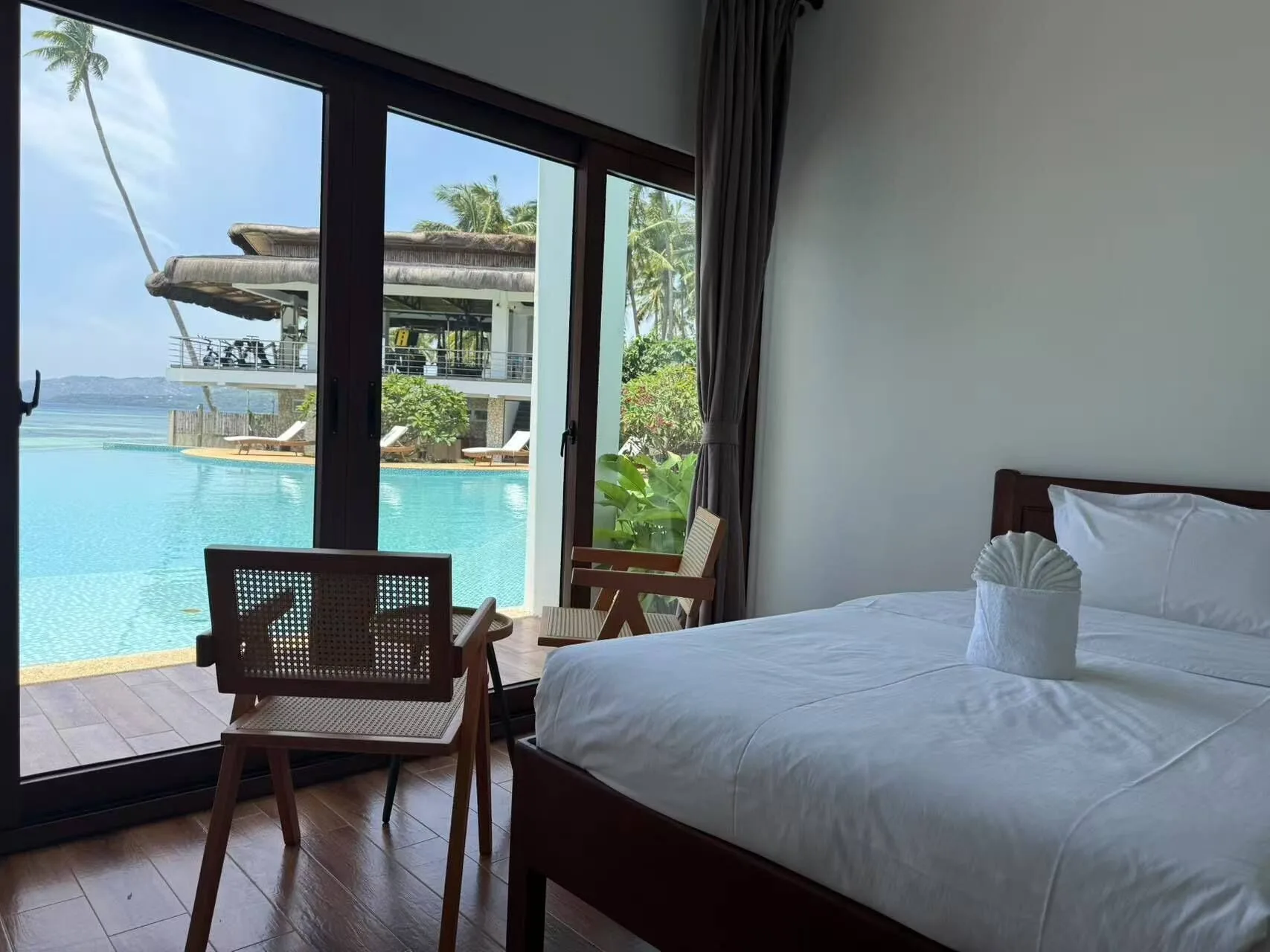 Luxury Room Beach View bed beside glass doors overlooking the pool and sea at Resort Deja Vu.