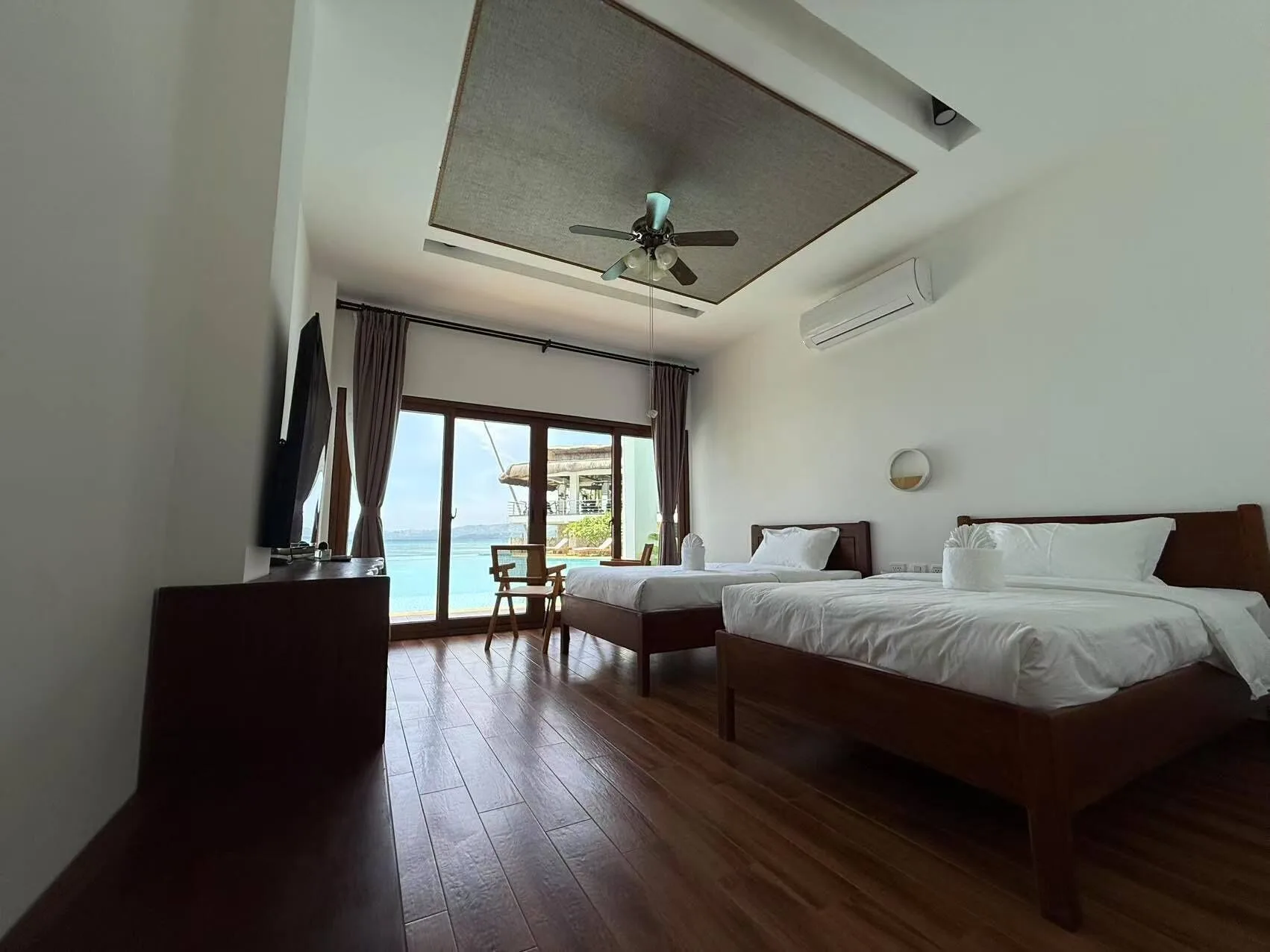Luxury Room Beach View with two beds, TV, wood floor, and glass doors at Resort Deja Vu.