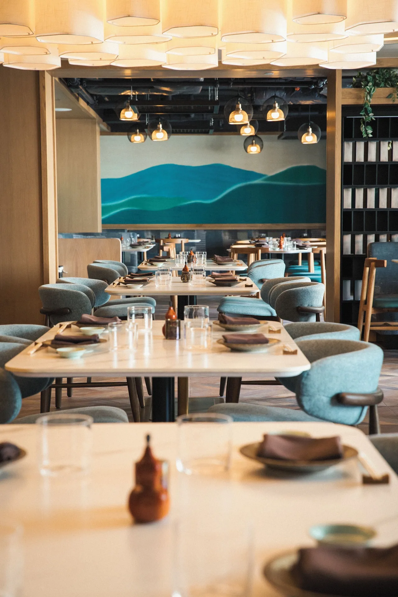 Dining room with set tables and teal chairs at Romer House Waikiki.