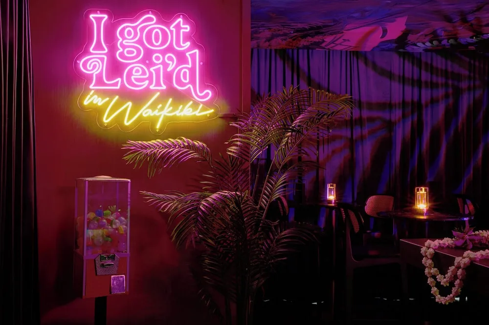 Neon sign and lounge seating at The Lei Stand Waikīkī at Romer House Waikiki.