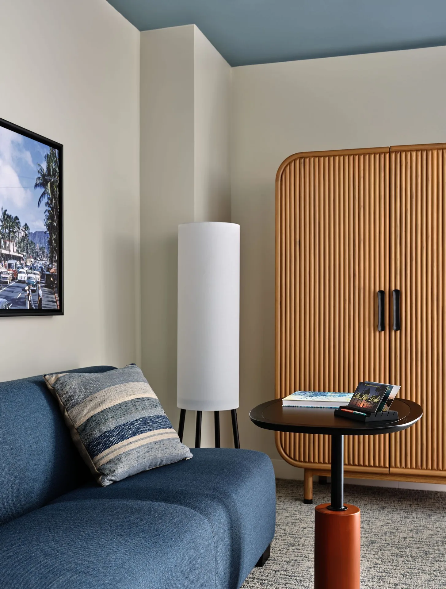 Blue lounge chair, floor lamp, round table and ribbed wardrobe at Romer House Waikiki.