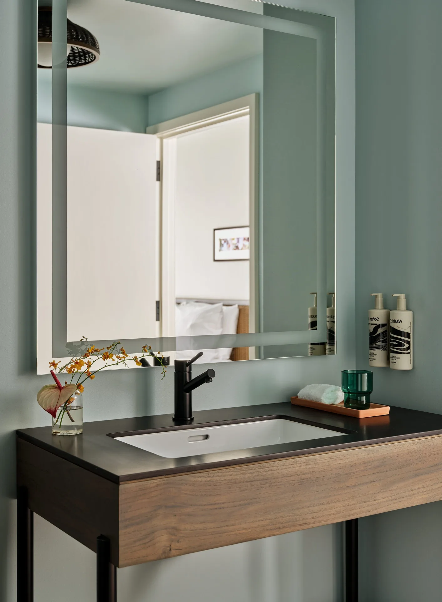 Standard room bathroom vanity at Romer House Waikiki with mirror, sink, and amenities.