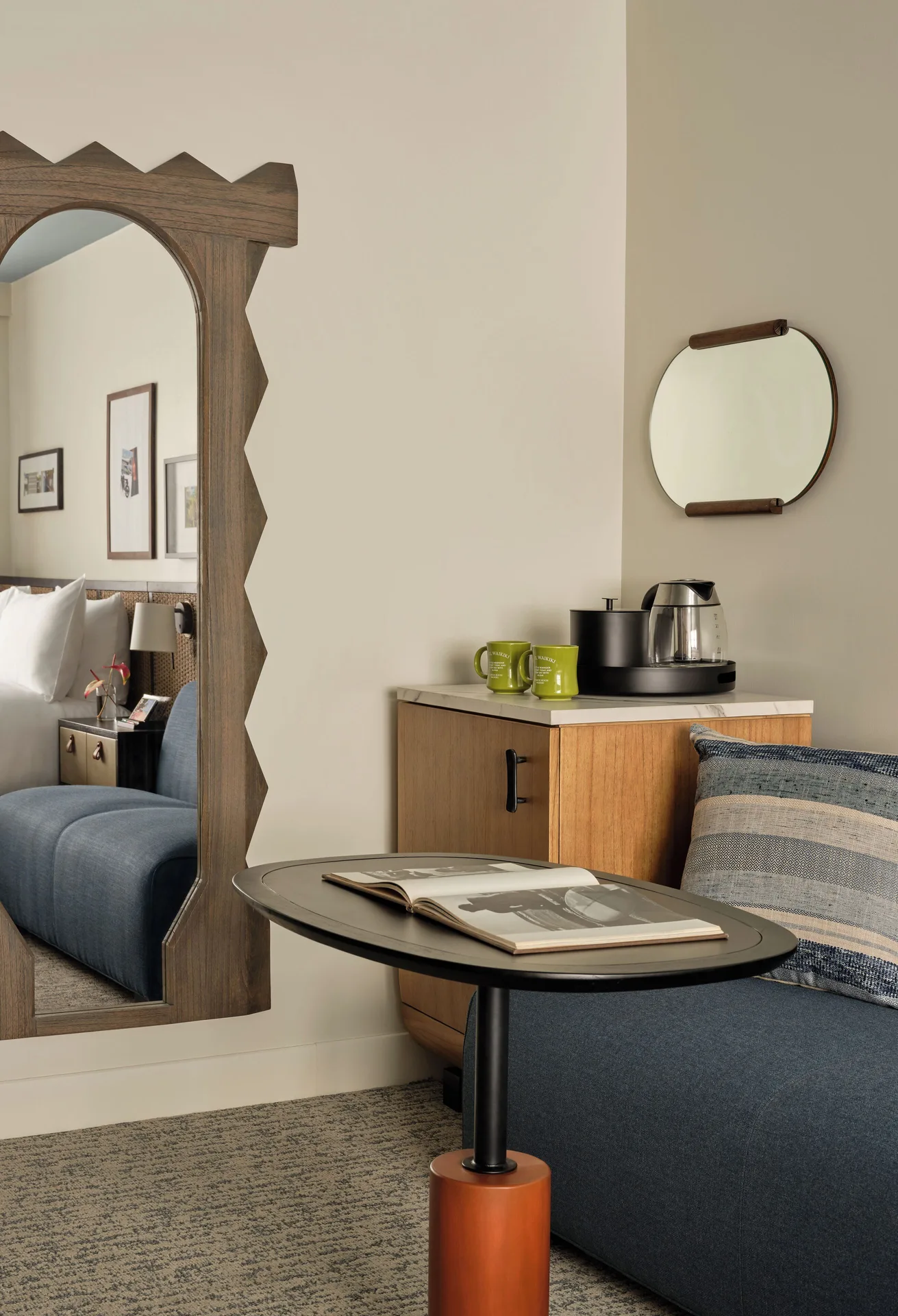 Standard room seating nook at Romer House Waikiki with lounge seat, table, mirror, and coffee setup.