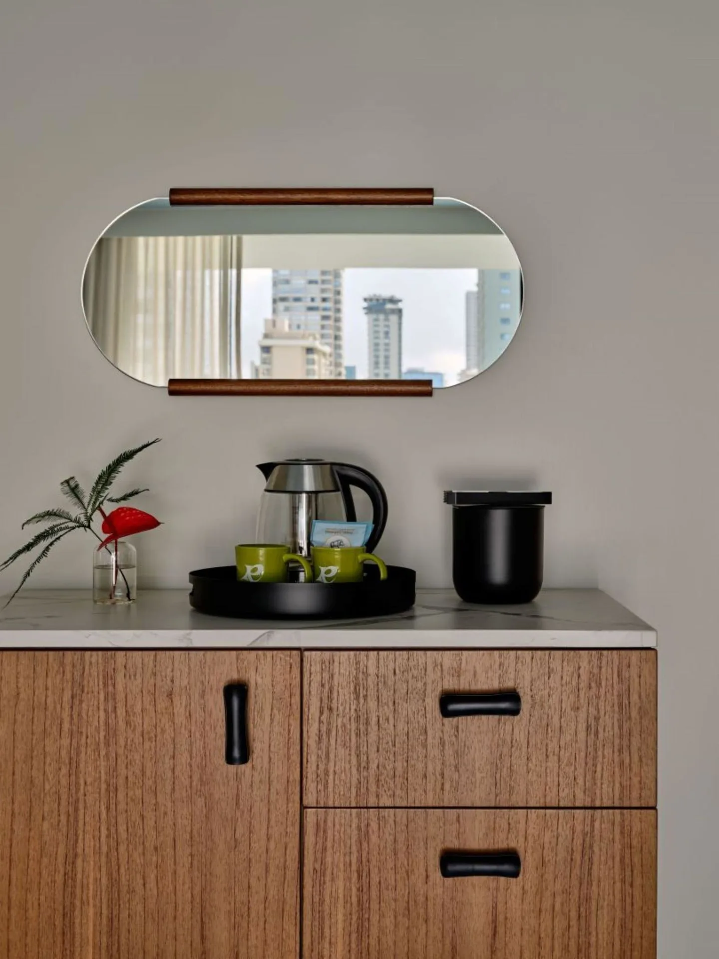 Standard Room refreshment cabinet with mirror, kettle, mugs, and flower at Romer House Waikiki.