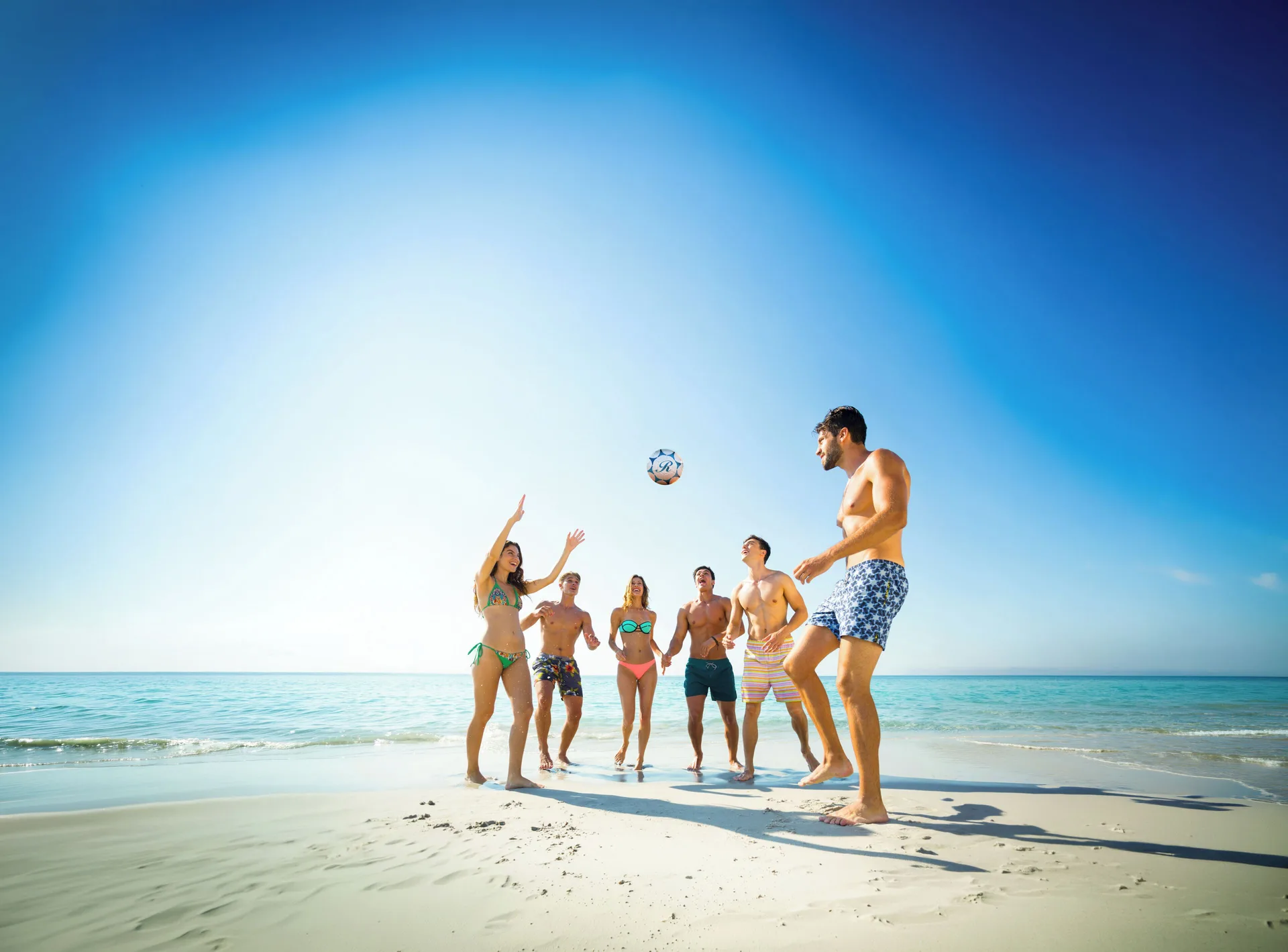 Guests playing beach soccer by the sea at Royalton CHIC Antigua.