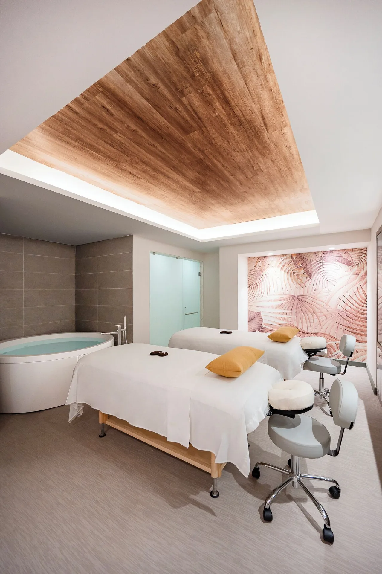 Spa treatment room with two massage tables and a round soaking tub at Royalton CHIC Antigua.