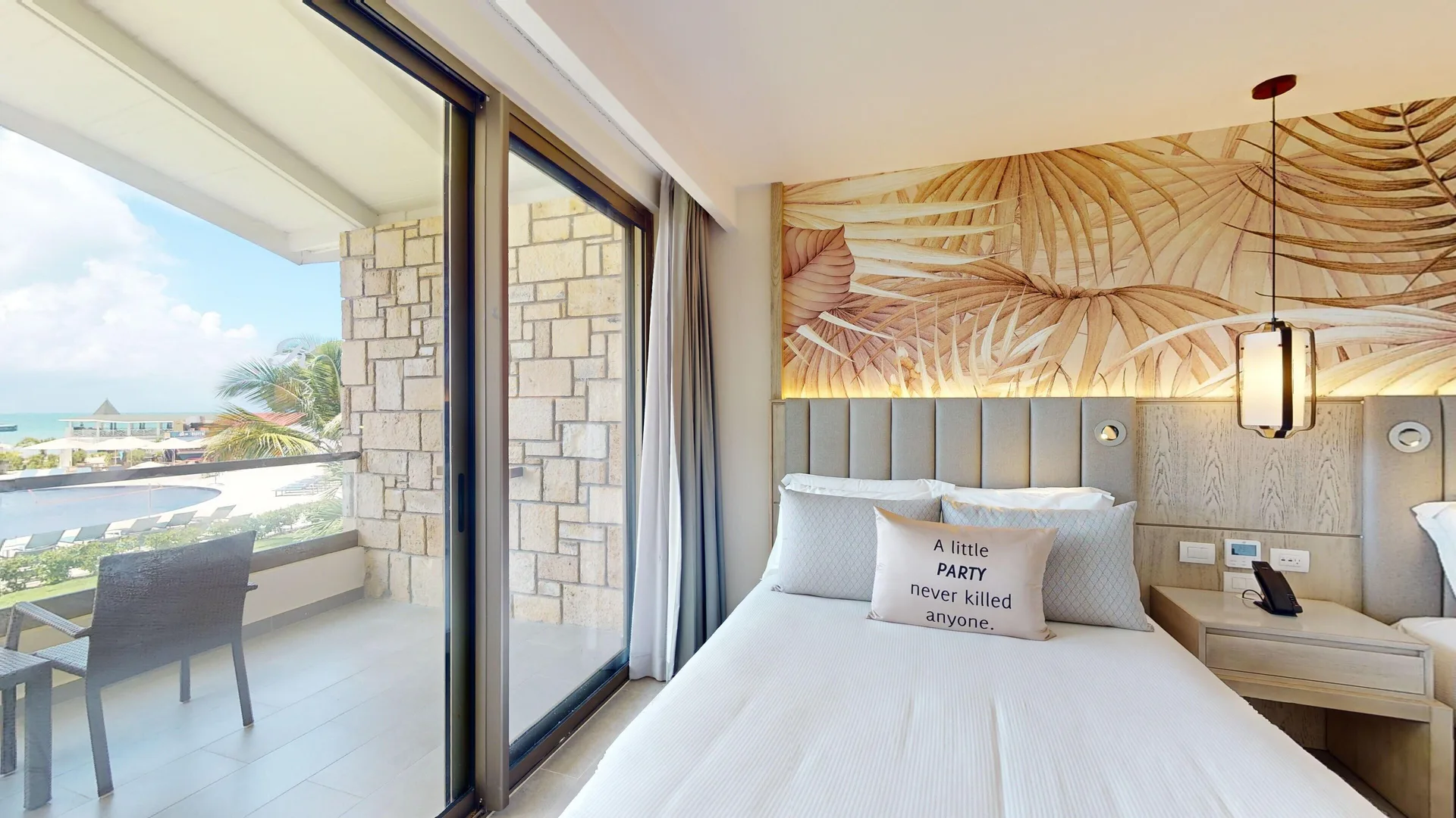 Queen bed beside balcony doors in a Luxury Garden View Room Diamond Club at Royalton CHIC Antigua.