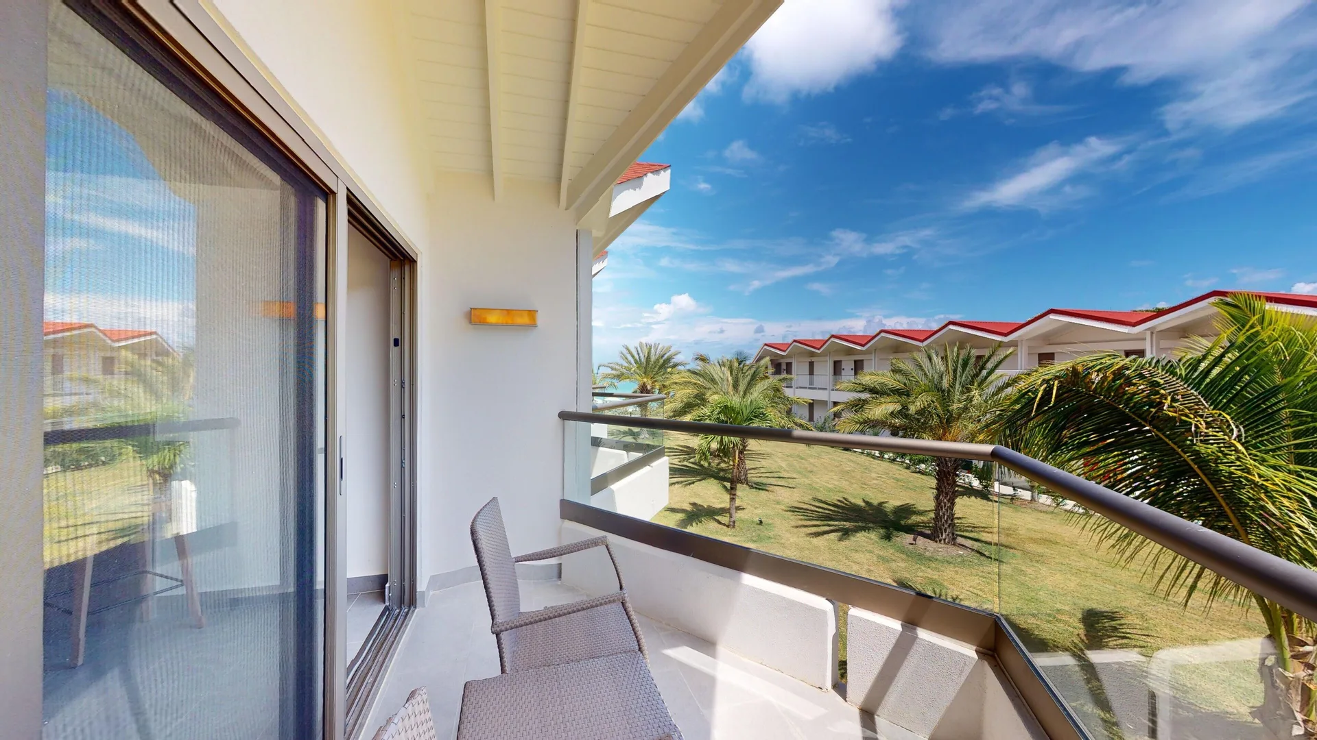 Furnished garden-view balcony outside a Luxury Garden View Room at Royalton CHIC Antigua.