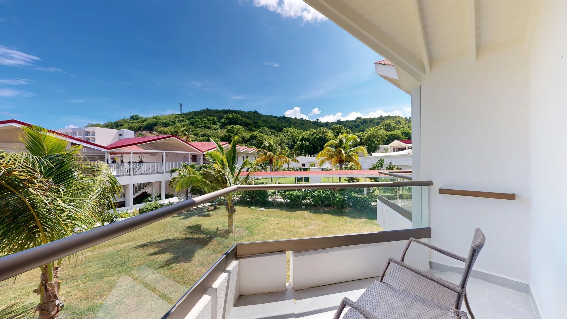 Luxury Garden View Room balcony with chairs and palm-lined grounds at Royalton CHIC Antigua.