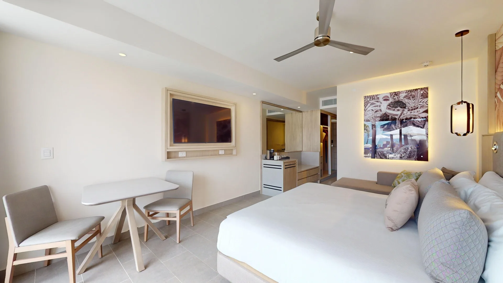 King bed, dining table, wall TV, and lounge seating in a suite at Royalton CHIC Antigua.