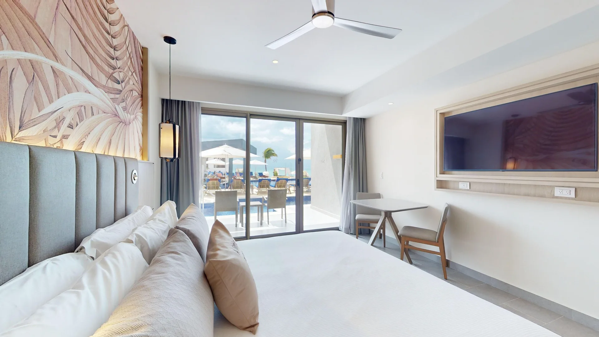 King bed facing terrace doors with pool and ocean beyond at Royalton CHIC Antigua.