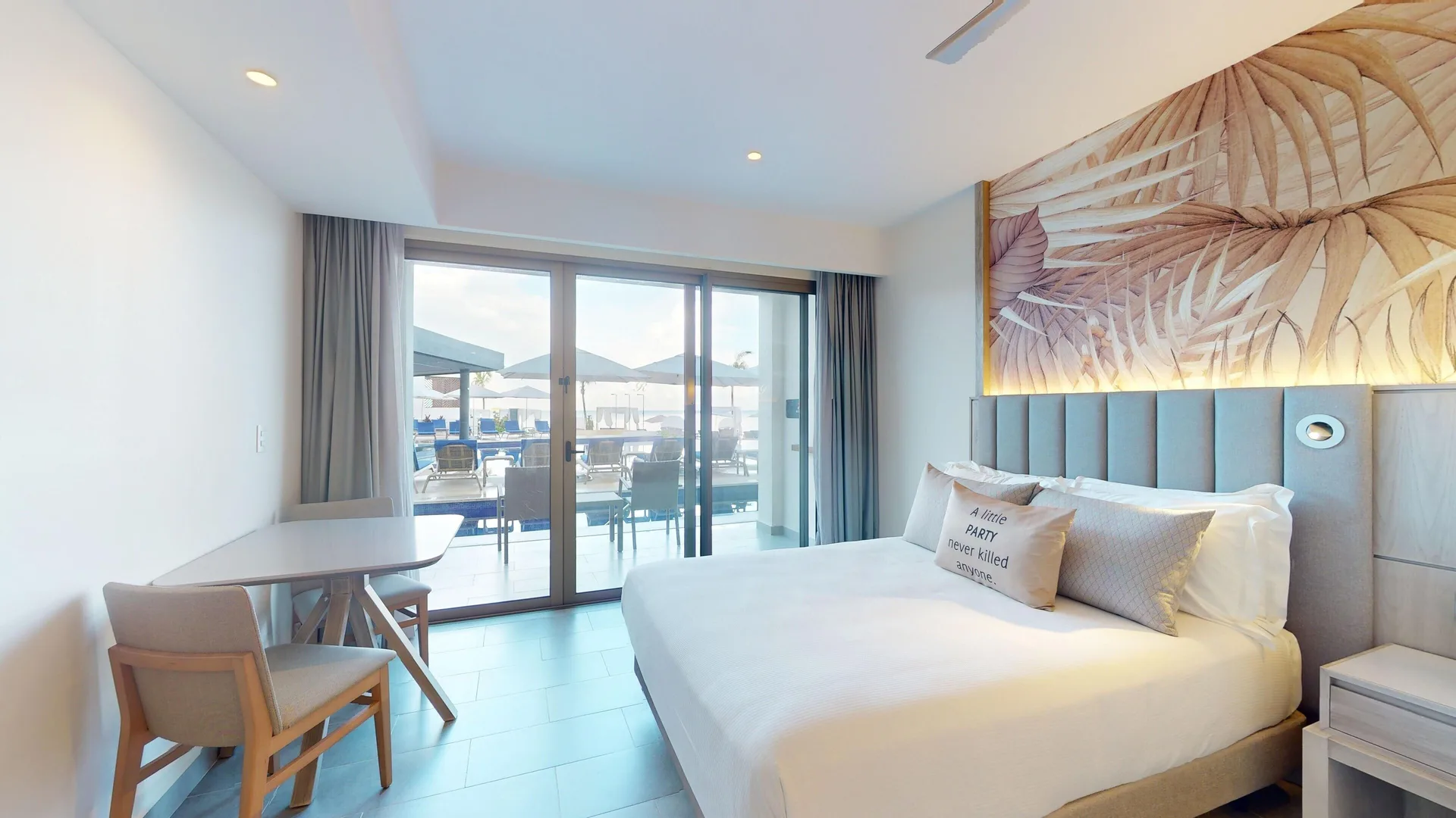 King bed in a beachfront swim-out junior suite at Royalton CHIC Antigua with terrace doors beside it.