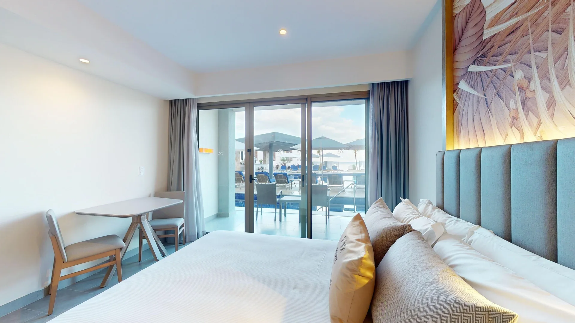 Beachfront swim-out junior suite bed at Royalton CHIC Antigua facing sliding doors to the terrace.
