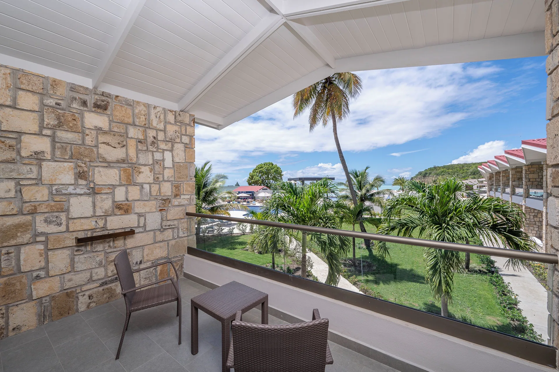 Furnished balcony with garden and water views in a Luxury Pool View Room at Royalton CHIC Antigua.