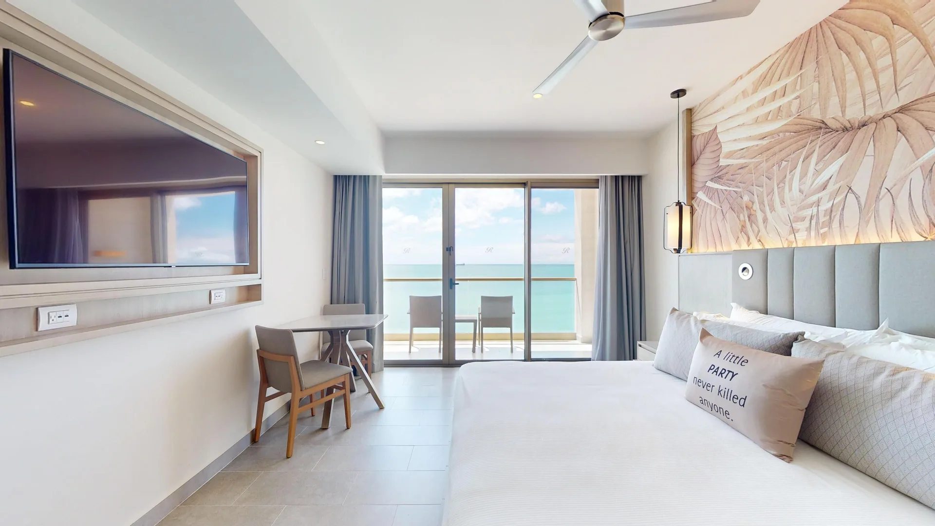 Oceanfront suite bedroom with king bed and balcony at Royalton CHIC Antigua.