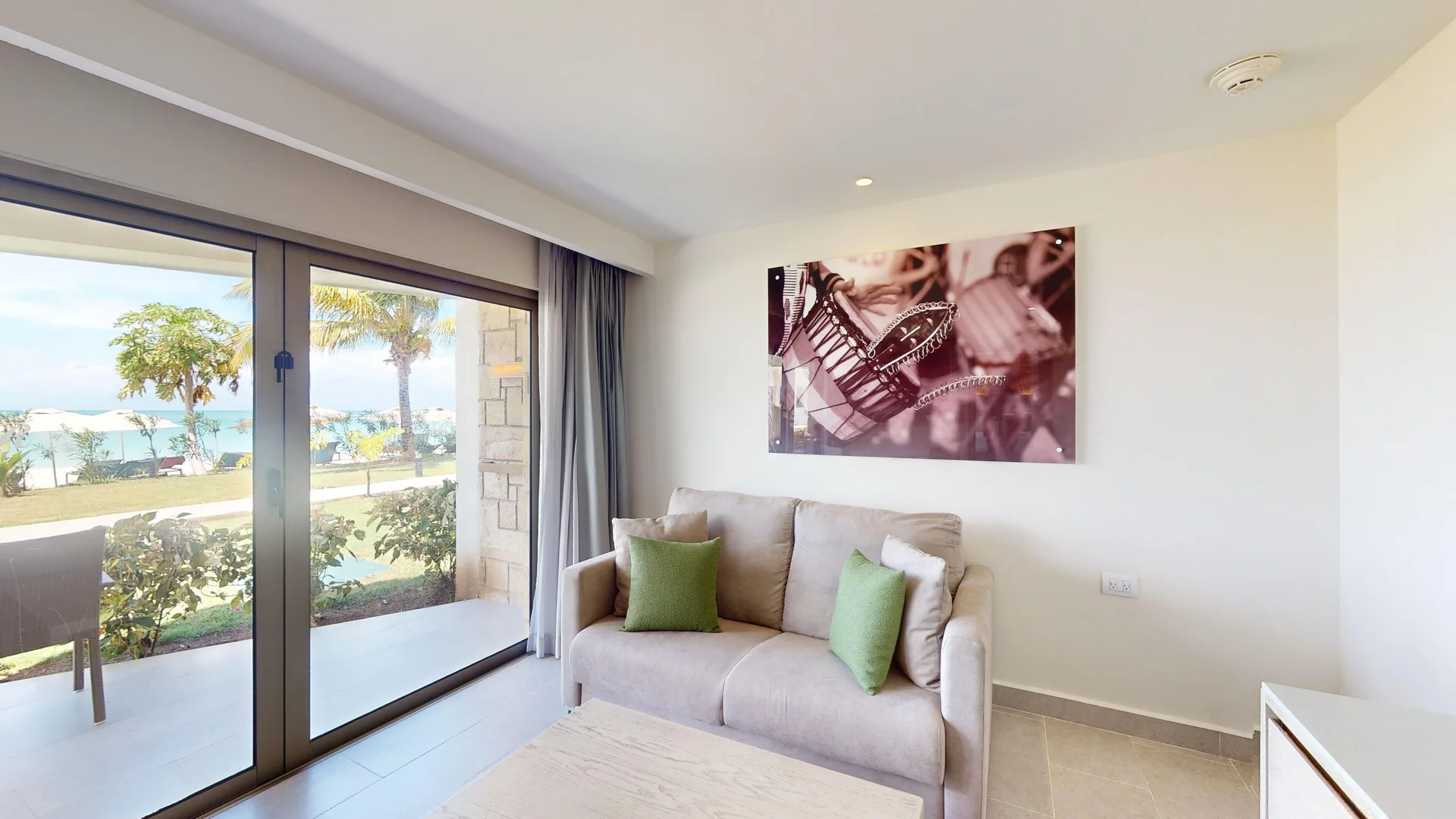 Beachfront walkout suite living area with sofa and patio doors at Royalton CHIC Antigua.