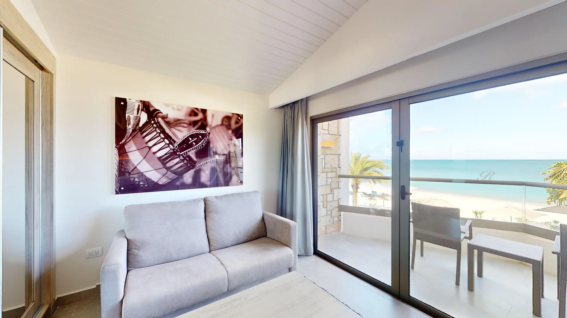 Suite sitting area with sofa and balcony ocean view at Royalton CHIC Antigua.