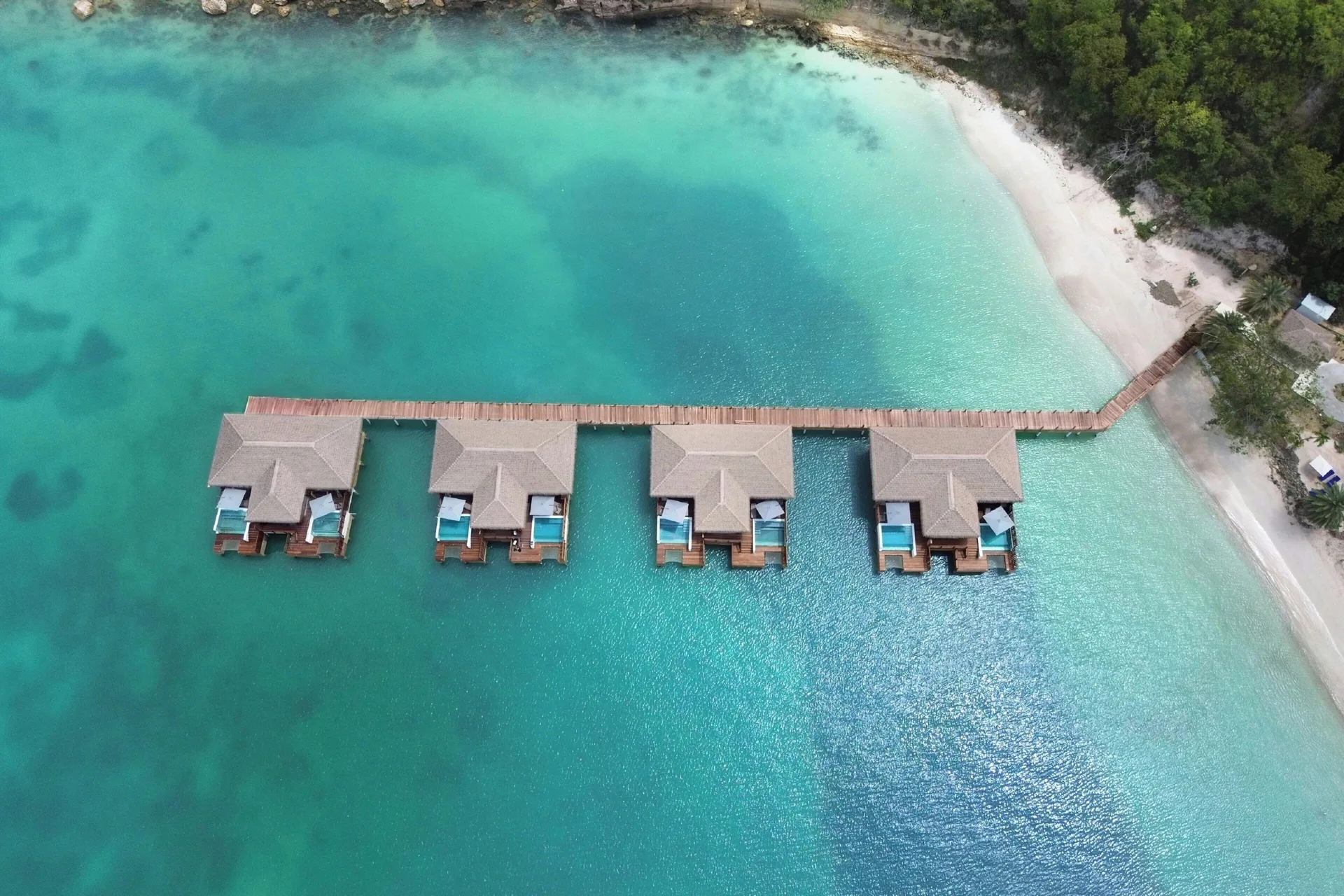 Top-down aerial of overwater suites beside a beach at Royalton CHIC Antigua.
