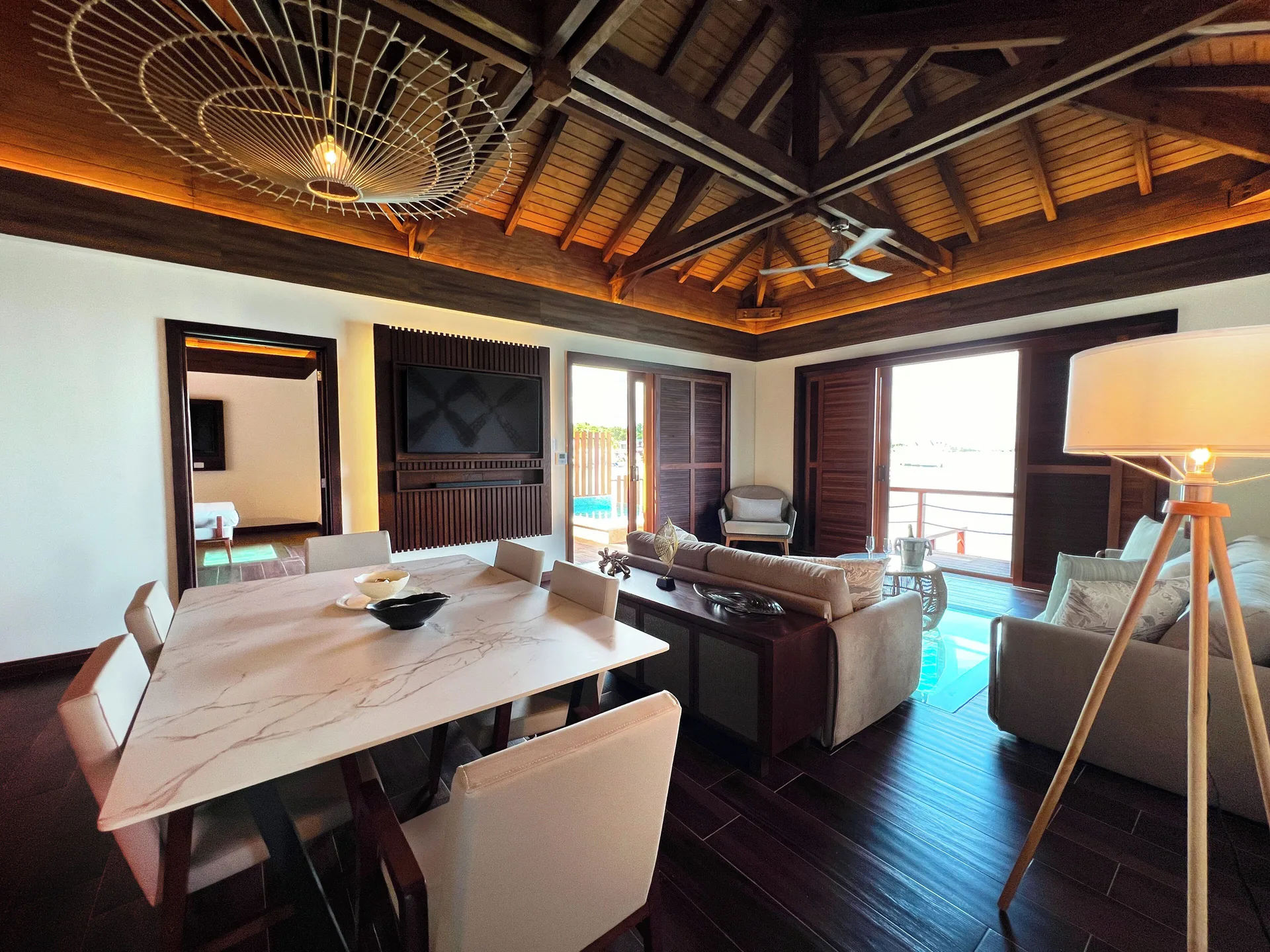 Dining and lounge area of an overwater suite at Royalton CHIC Antigua with deck doors open.