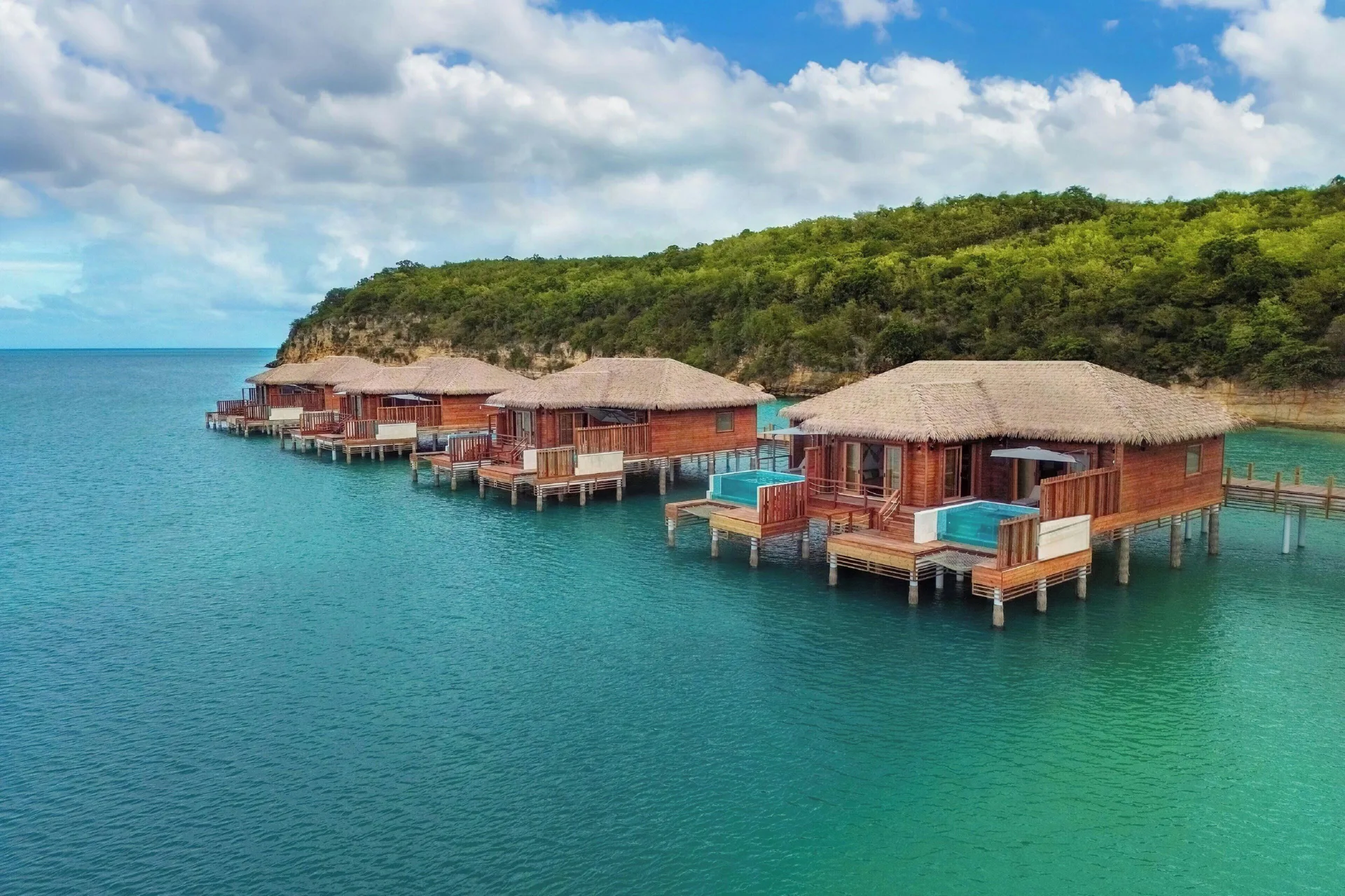 Row of overwater suites with private decks over the sea at Royalton CHIC Antigua.