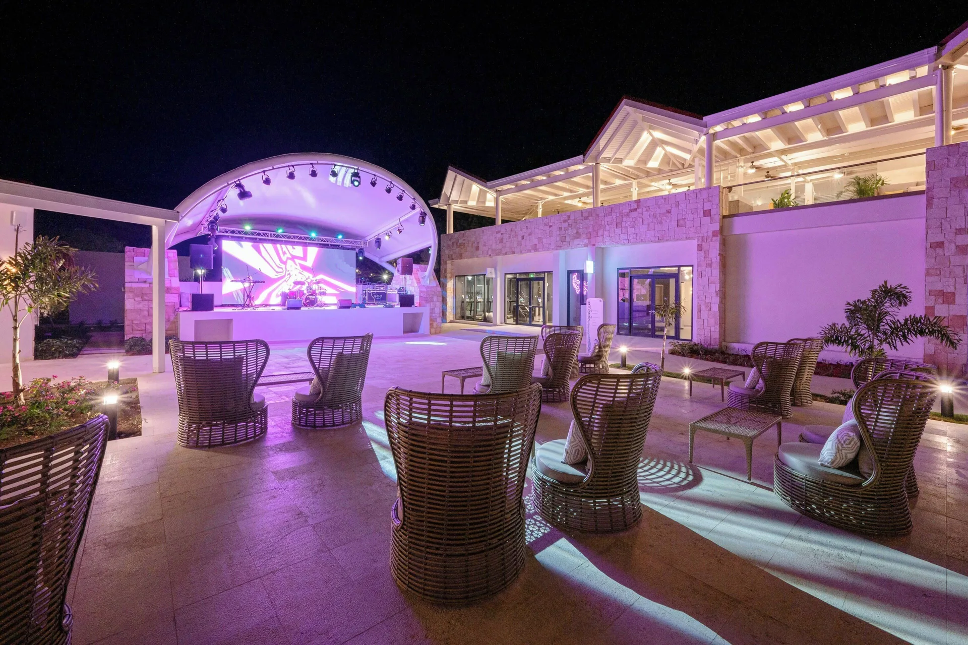 Outdoor stage and wicker lounge chairs at night at Royalton CHIC Antigua.