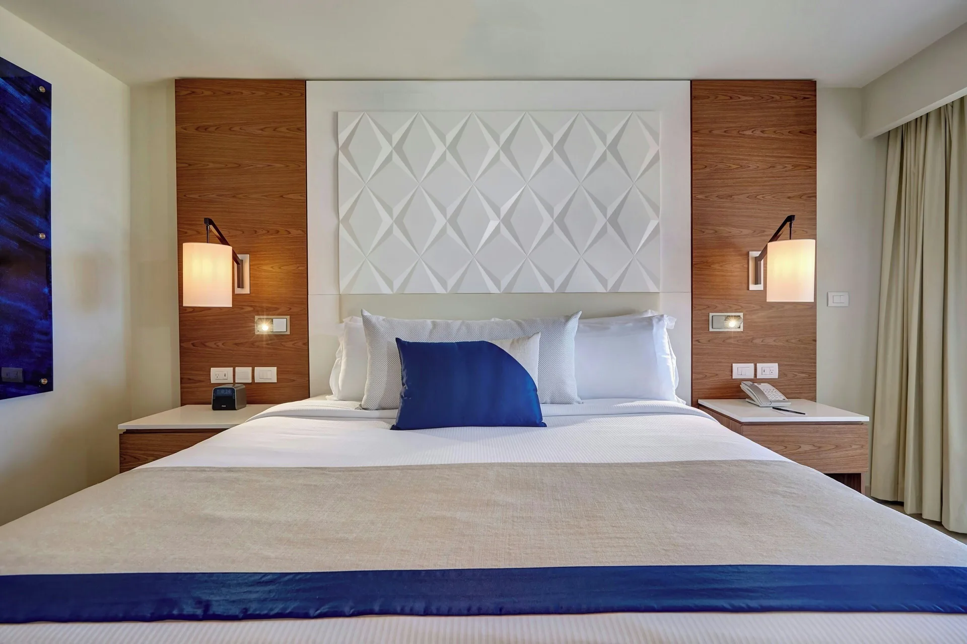 Oceanfront suite king bed with geometric headboard at Royalton Grenada.