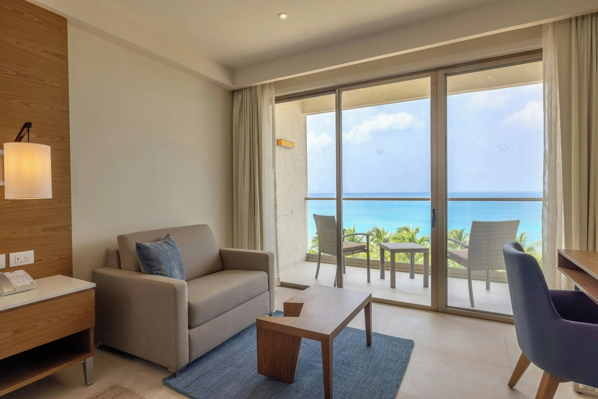Sitting area and balcony in a Luxury Junior Suite Ocean Front Diamond Club at Royalton Grenada.