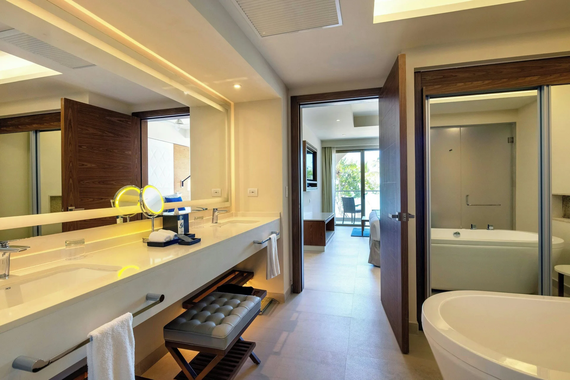 Suite bathroom with double sinks, vanity mirrors, tub, and bedroom beyond at Royalton Grenada.