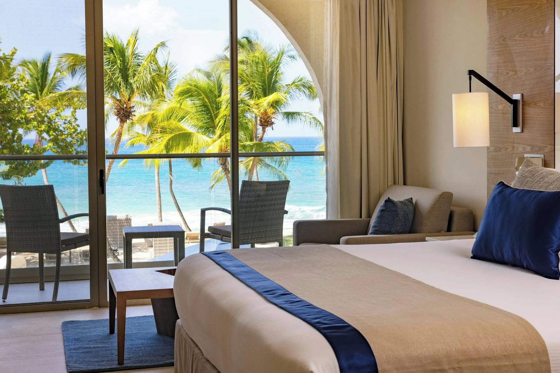 Oceanfront king bedroom with balcony seating in a suite at Royalton Grenada.