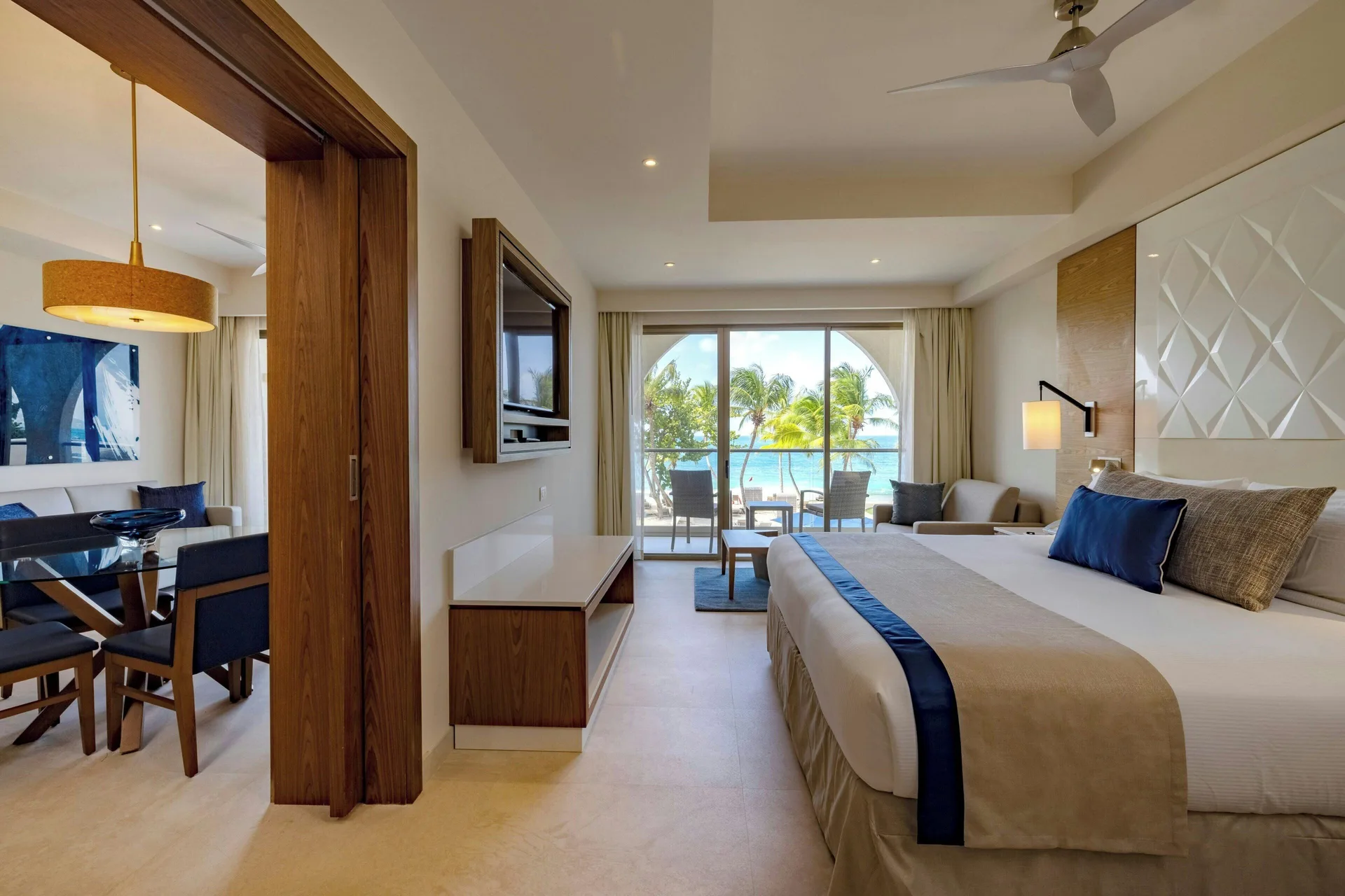 Oceanfront suite bedroom with king bed and living area doorway at Royalton Grenada.