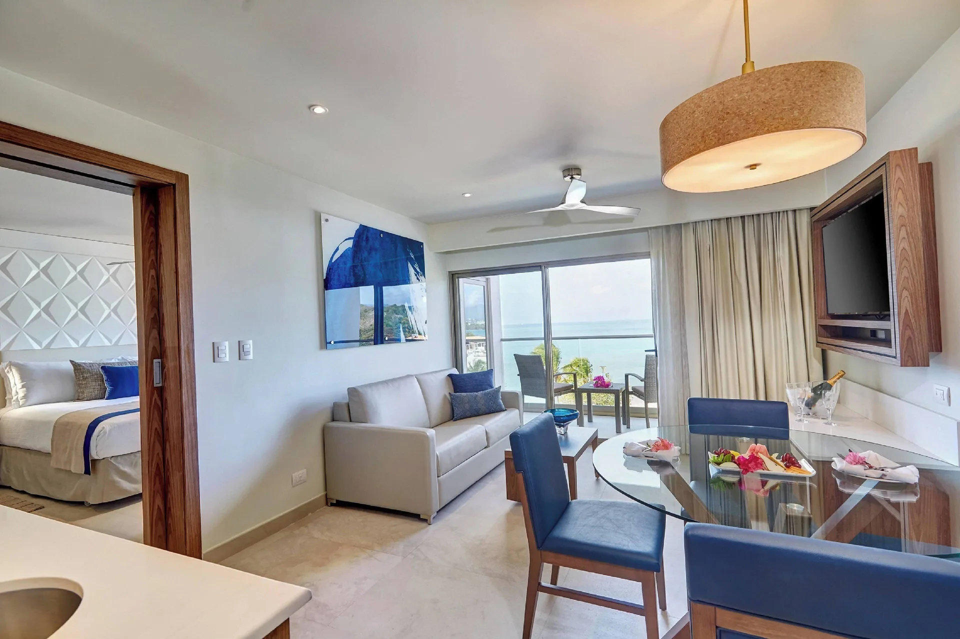 Oceanfront suite living room with dining table, sofa, and bedroom doorway at Royalton Grenada.